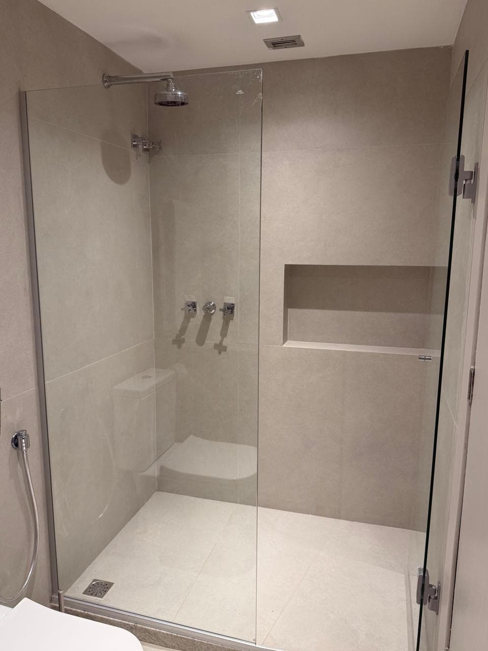 Banheiro com box, chuveiro de teto e ducha manual em porcelanato