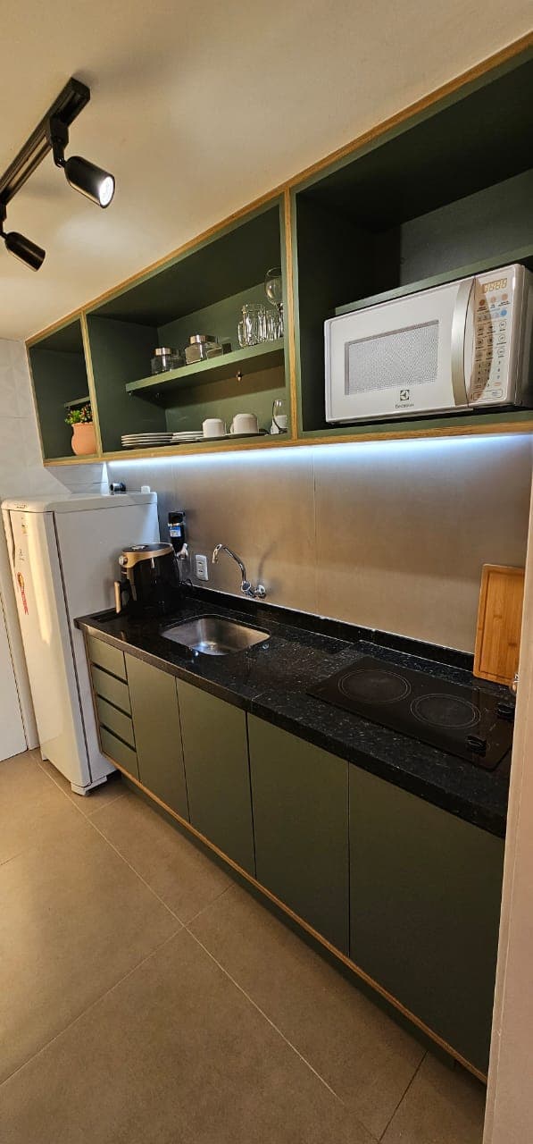 Cozinha compacta com cooktop e armários verdes