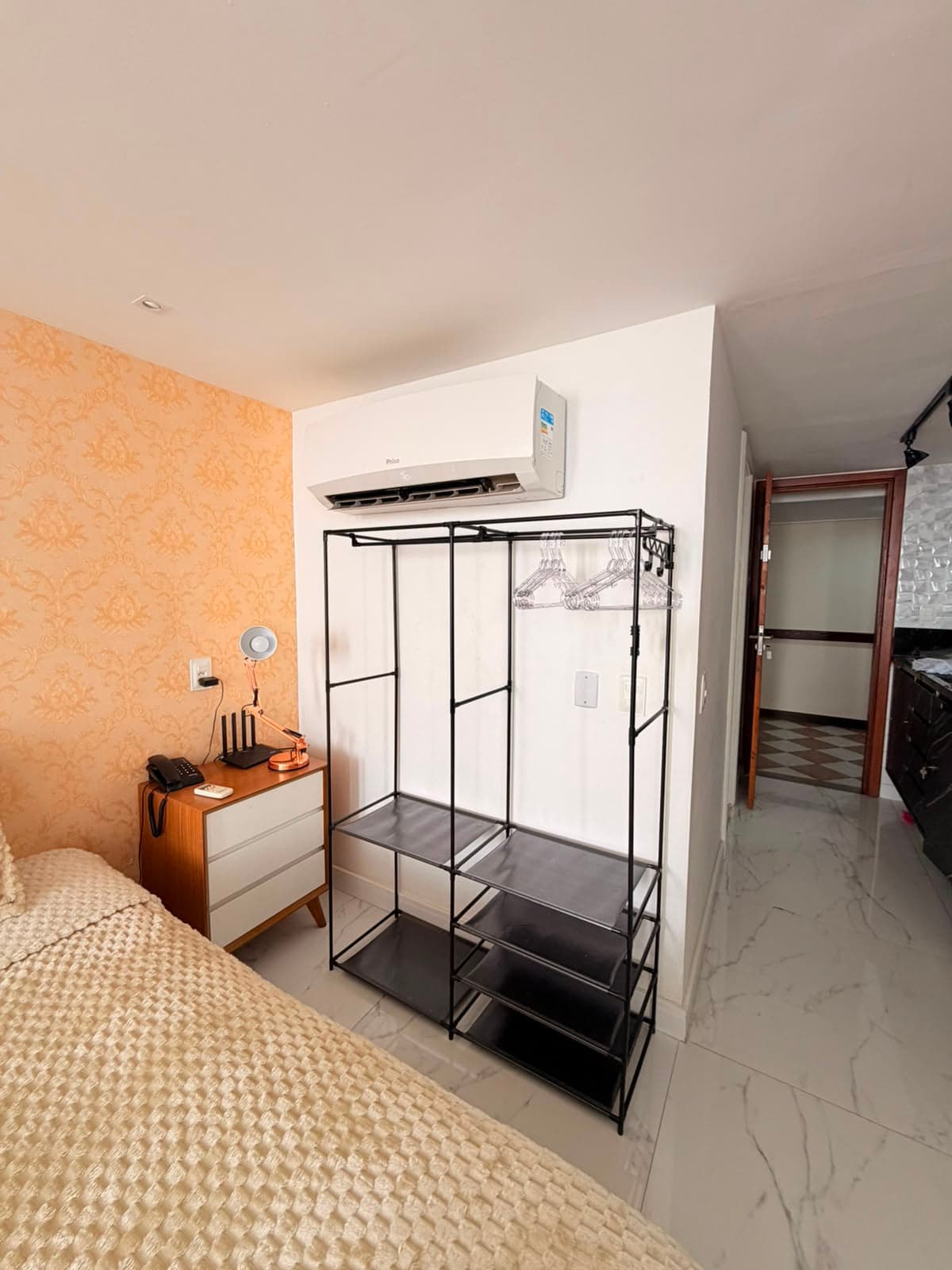 Quarto com cama de casal, arara de roupas e ar-condicionado