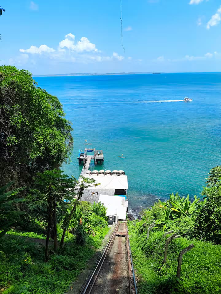 Trilho do bondinho descendo a encosta até o Píer Mahi Mahi, com a Baía de Todos os Santos ao fundo